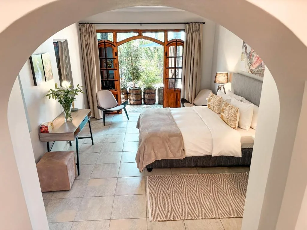 Spacious bedroom with queen bed, wooden doors opening to garden view