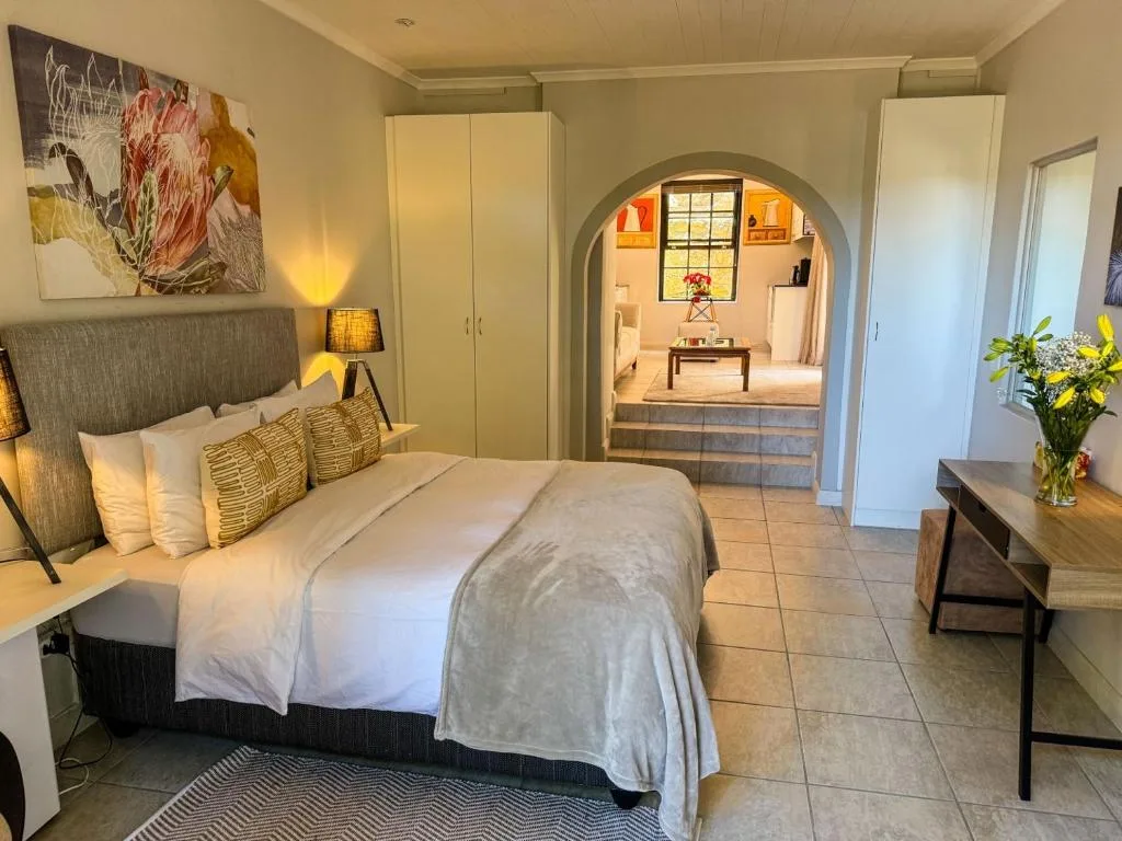 Spacious bedroom with queen bed, wardrobe, and archway to lounge area