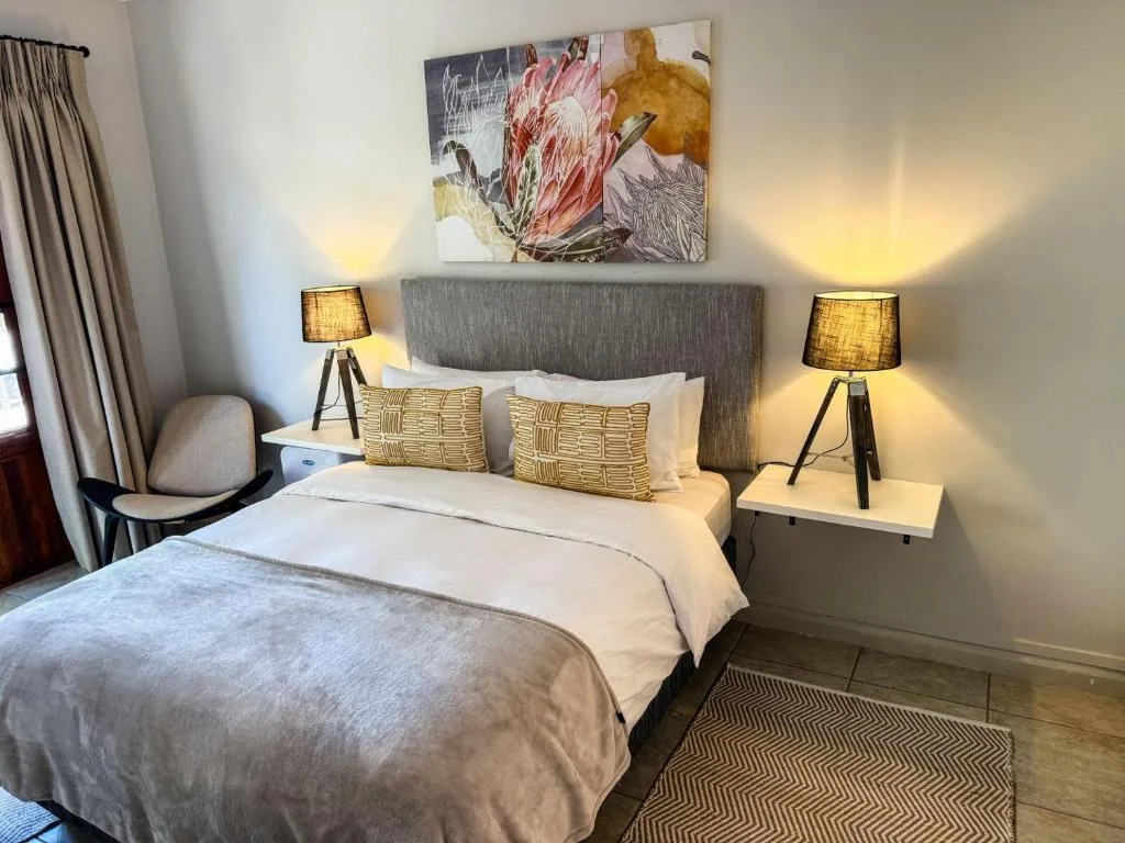 Contemporary bedroom with queen bed, gray upholstered headboard, and warm lighting