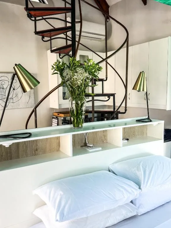 Modern bedroom with white pillows and contemporary spiral staircase above headboard