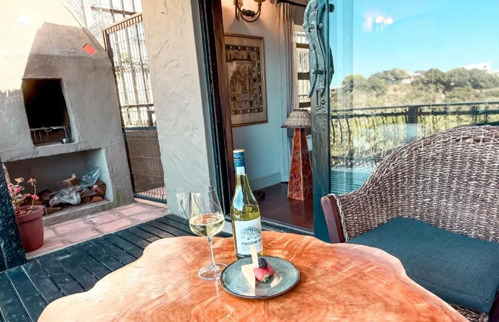 Outdoor deck with wine and lagoon views, wicker seating, braai area