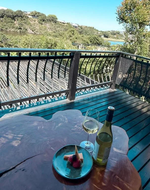 Blue wooden deck with wine and snacks overlooking lagoon and hills