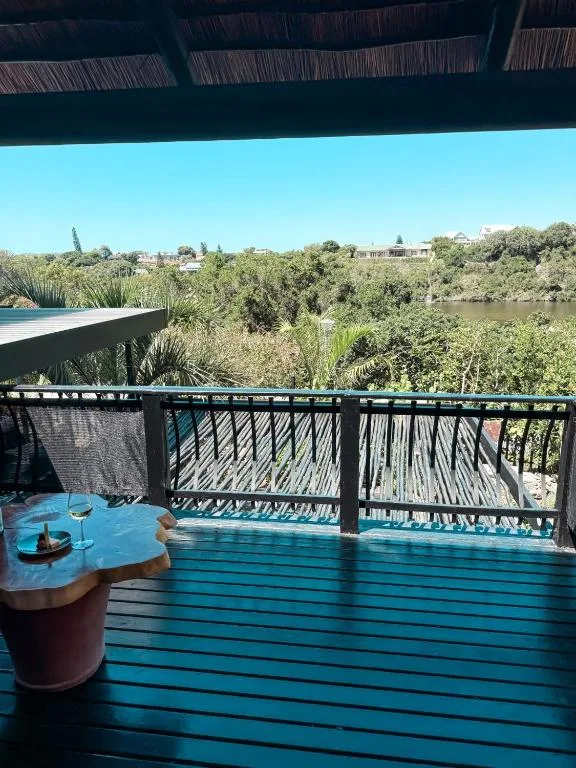 Blue wooden deck with river and vegetation views, shaded pergola overhead
