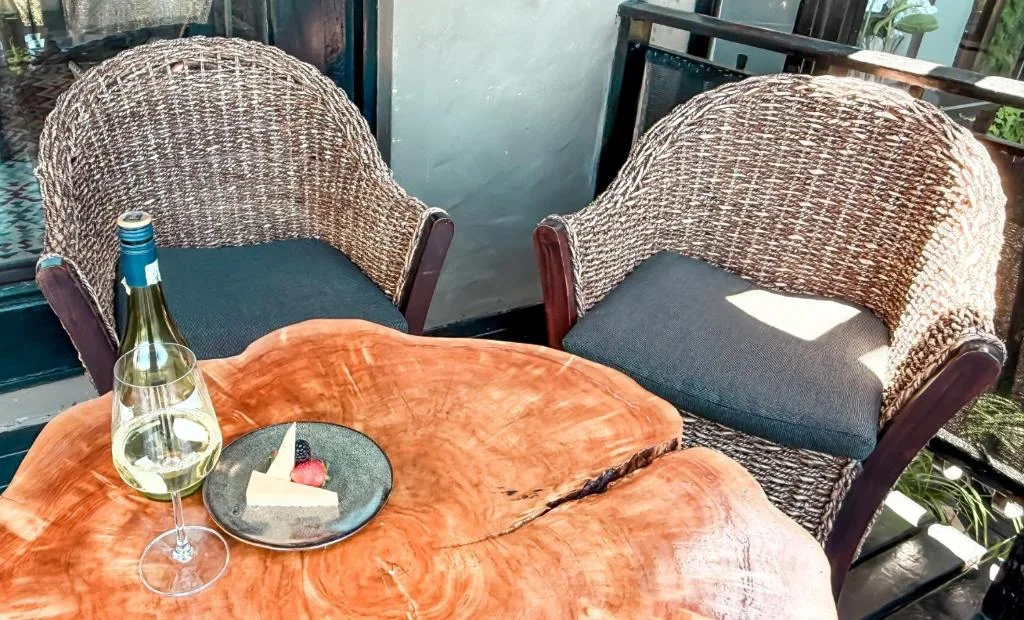 Outdoor seating area with wicker chairs and wooden table overlooking water