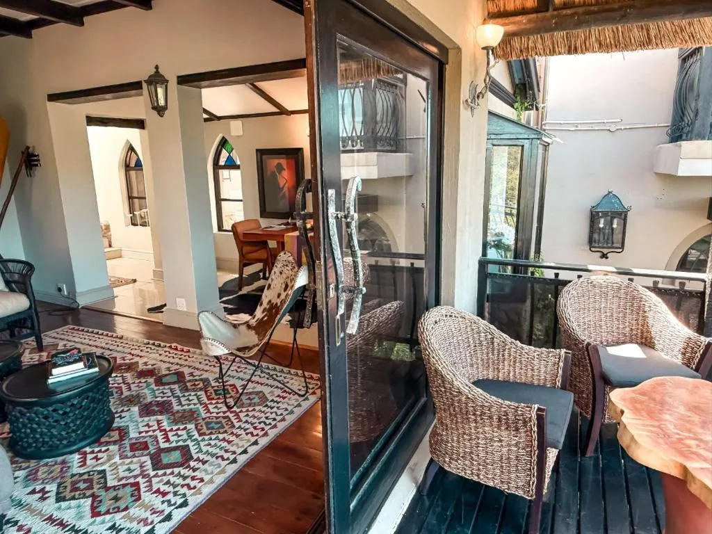 Wicker chairs on wooden deck with interior lounge view through glass doors