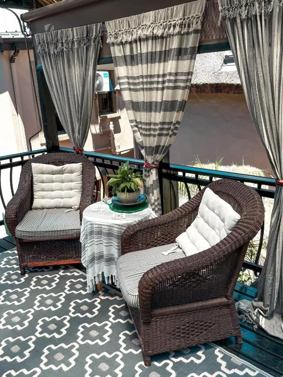 Shaded outdoor seating area with wicker chairs and striped curtains