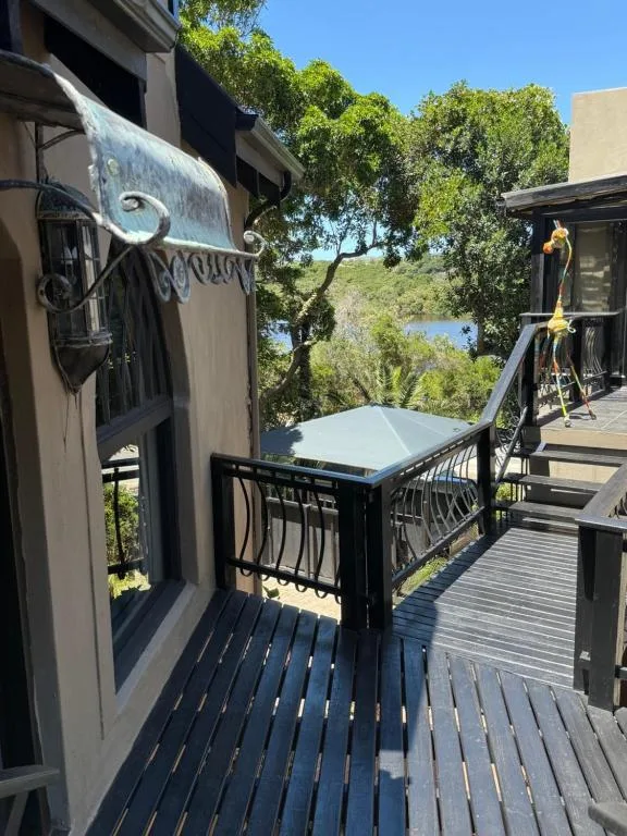 Wooden deck with outdoor dining table overlooking lagoon and vegetation