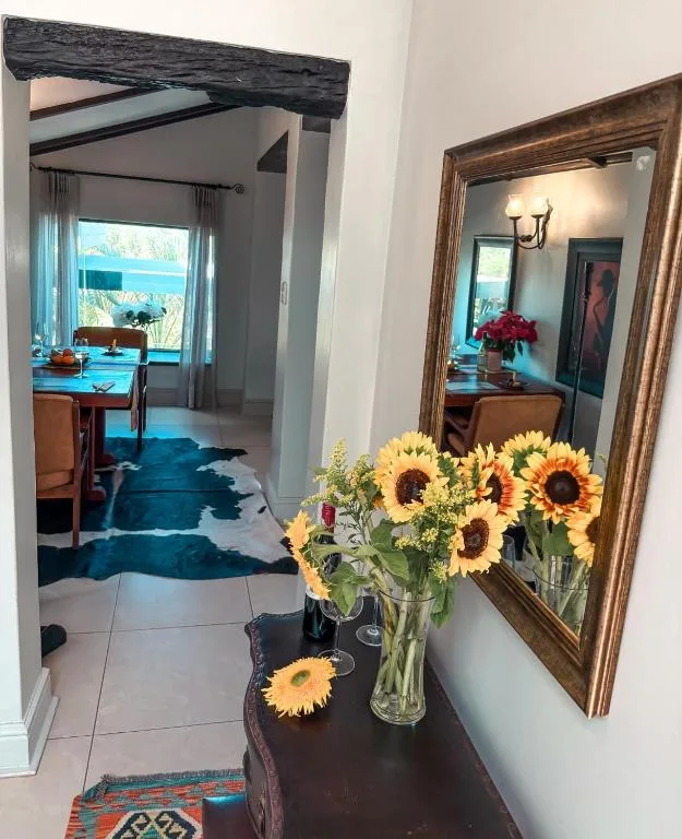 Fresh sunflowers in vase beside mirror, welcoming interior hallway