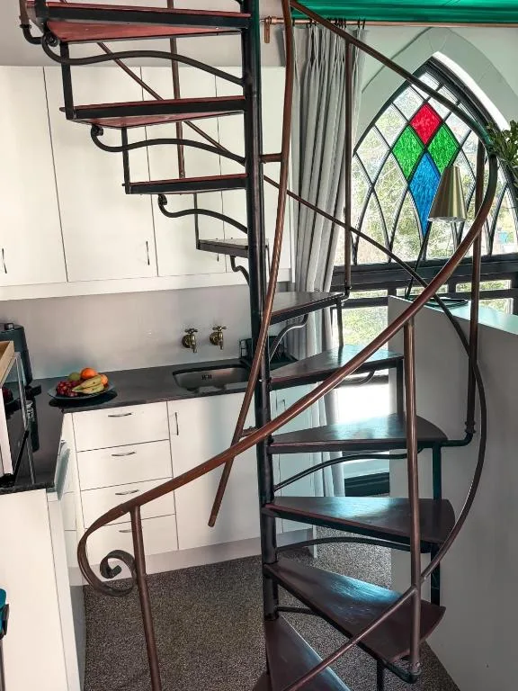 Spiral staircase with decorative stained glass window and kitchen visible