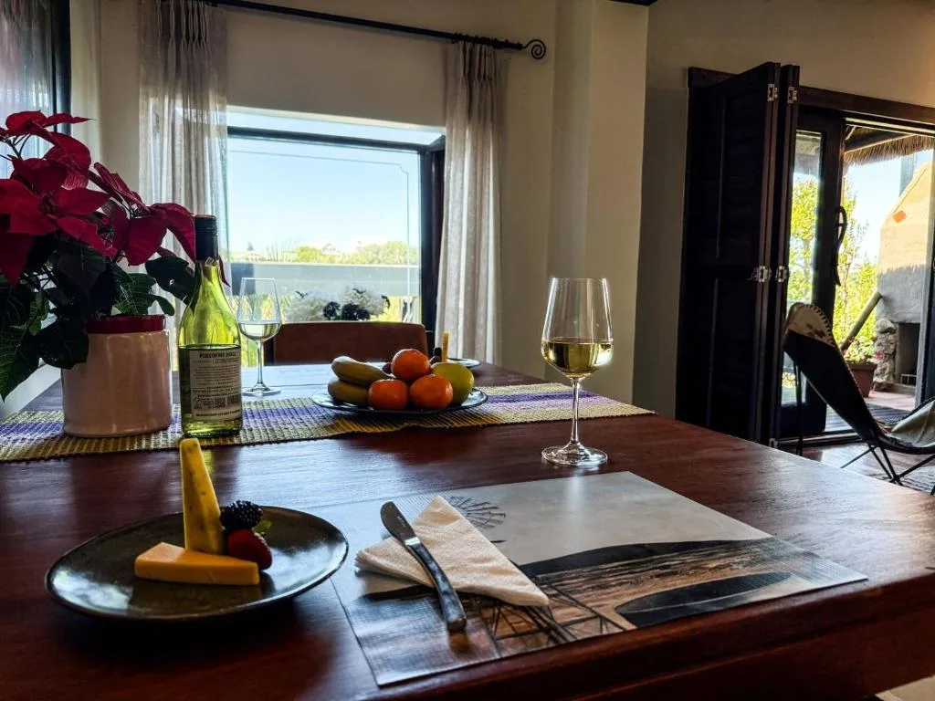Elegant dining table with wine, cheese, fruit, and lagoon views through windows