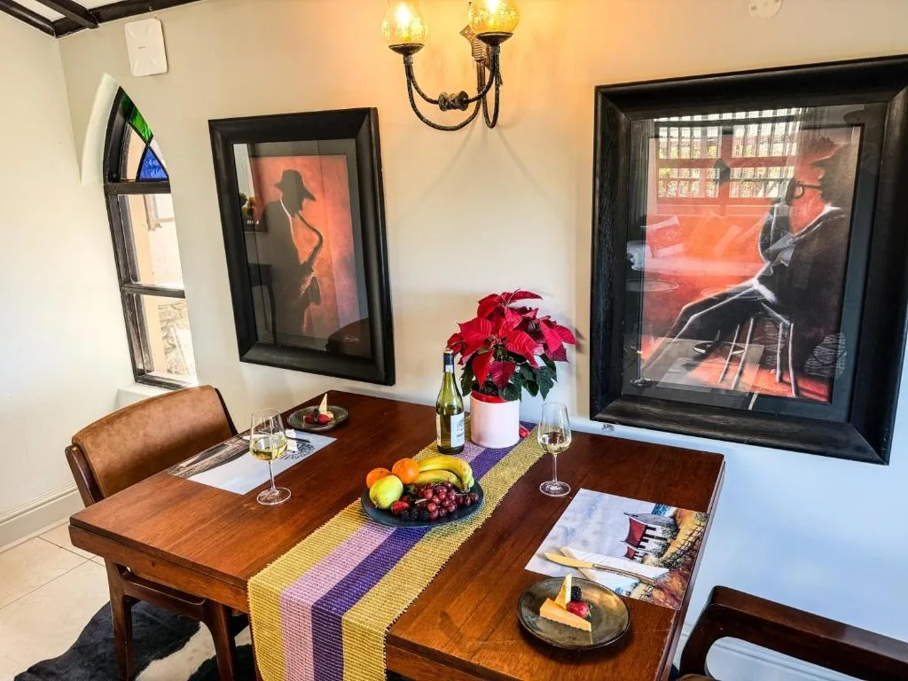 Wooden dining table set with wine glasses, fresh fruit, and red poinsettia flowers