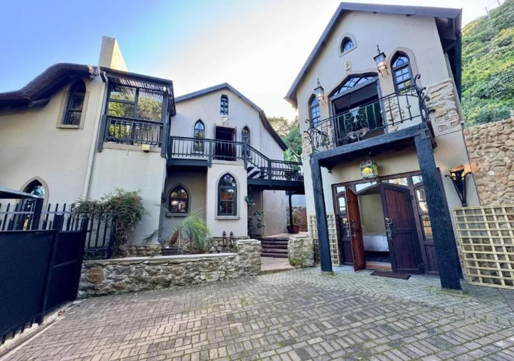 Charming white cottage with stone accents and multiple balconies in Wilderness