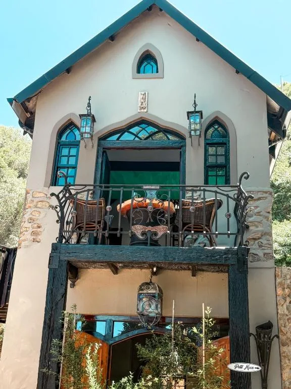 Charming two-story cottage with turquoise trim and decorative balcony