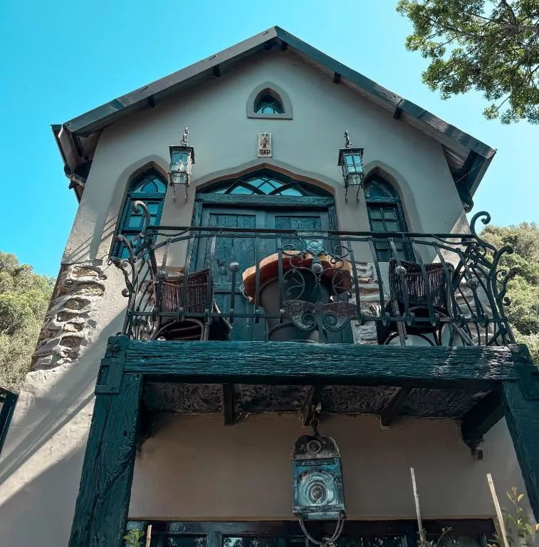 Whitewashed cottage facade with turquoise wooden balcony and decorative ironwork railings