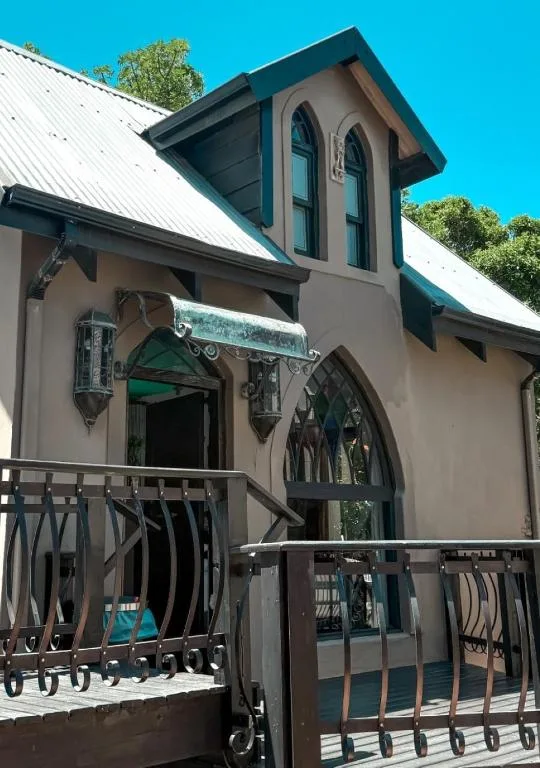 Charming cottage facade with dark green shutters and wooden deck railing
