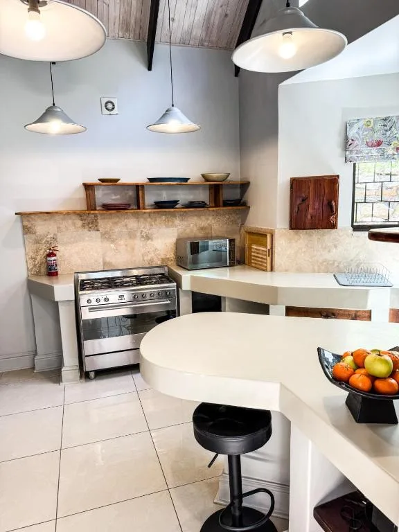 Modern kitchen with stove, white counters, pendant lighting, and bar seating