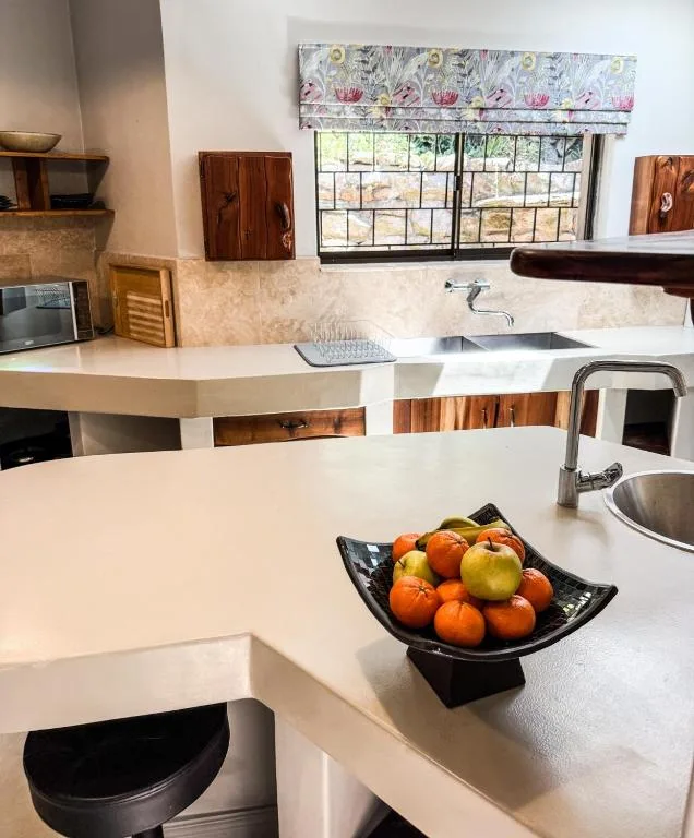 Modern kitchen with white counters, stainless steel sink, and fruit display