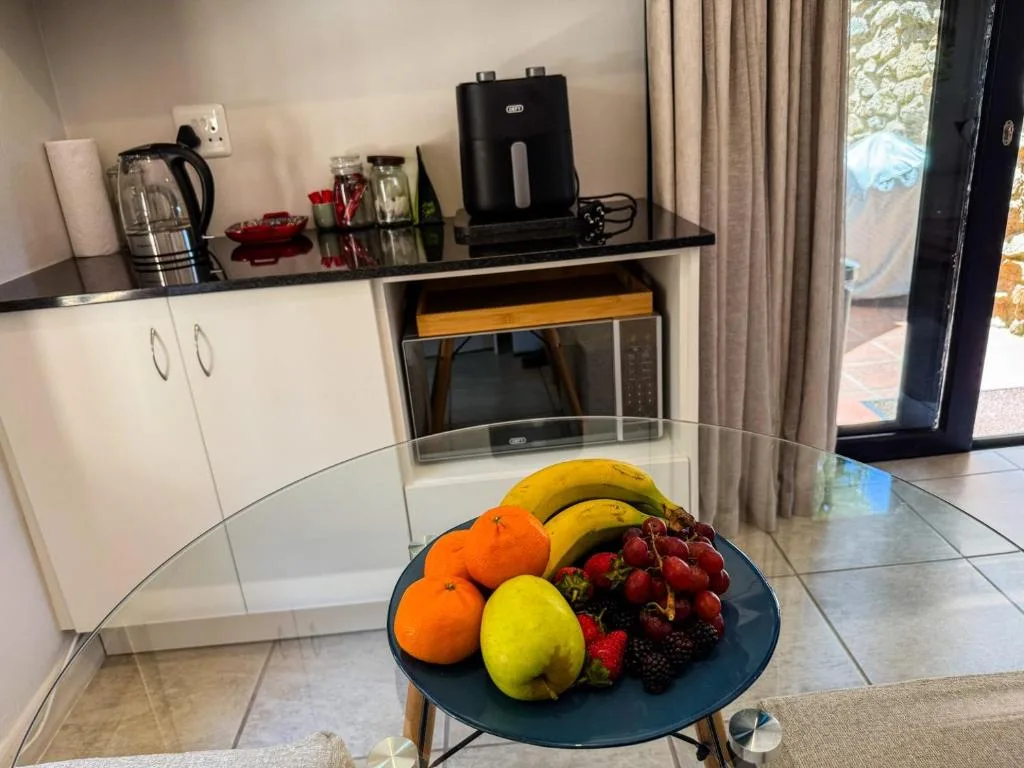 Modern kitchenette with white cabinetry, black countertop, and fresh fruit bowl