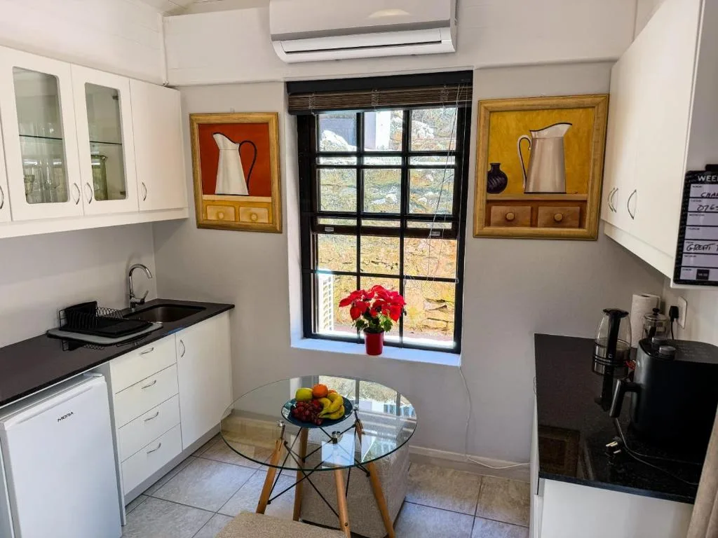 Bright kitchen with white cabinetry, black counters, and garden view window