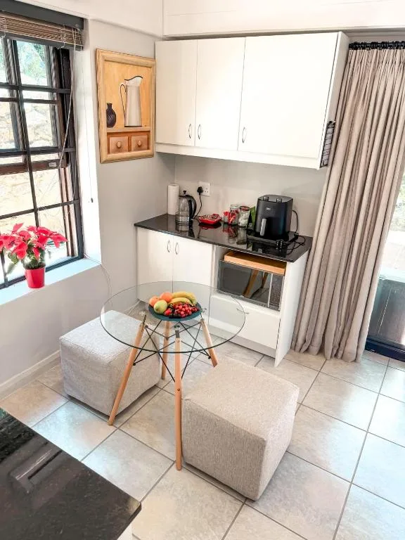 Compact kitchen with white cabinetry, black countertop, and small dining table
