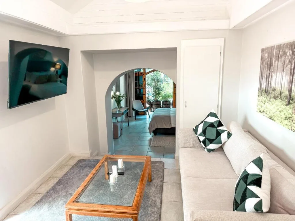 Modern lounge with sofa, coffee table, TV, and archway to bedroom