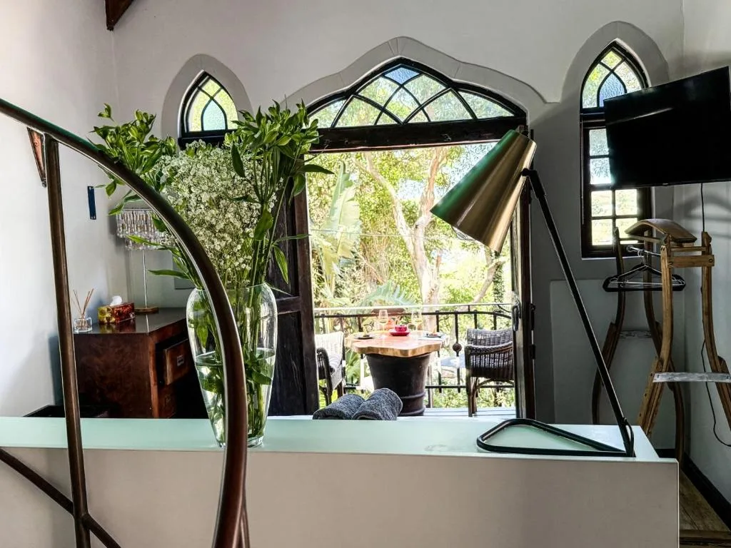 Modern lounge with desk, flowers, and large windows overlooking garden