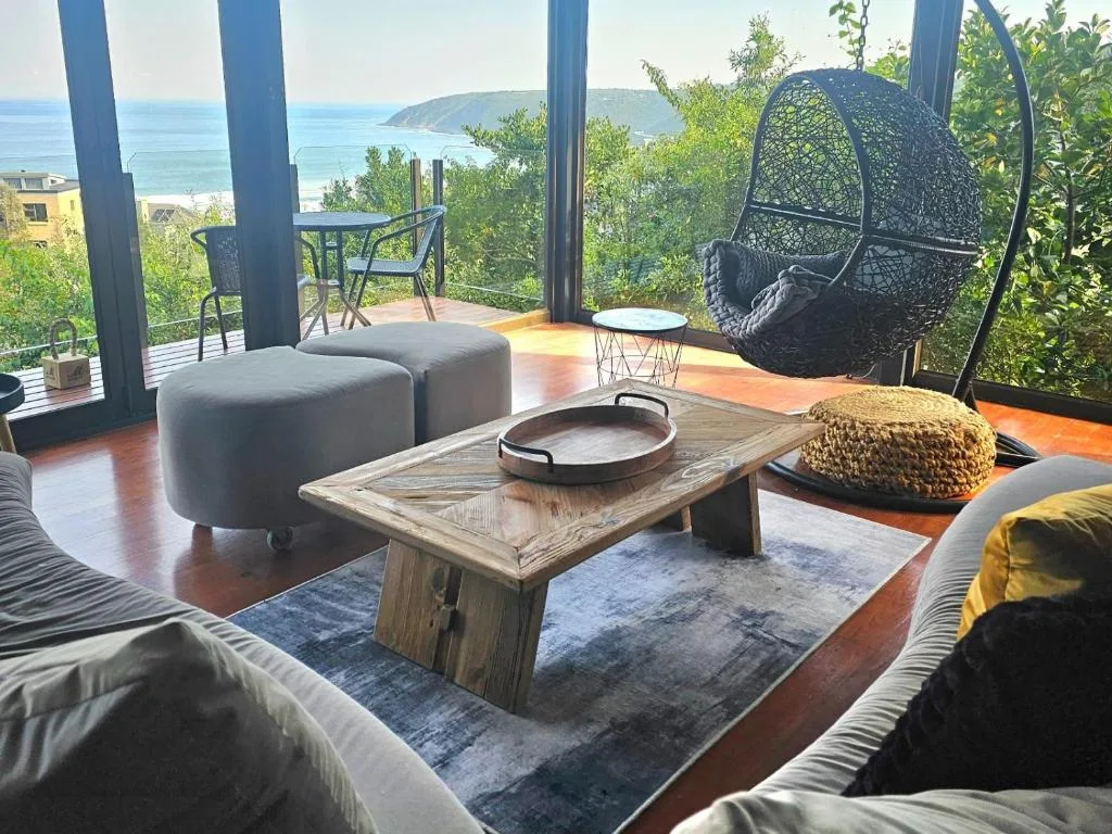 Oceanview deck with hanging chair, seating, and coastal landscape beyond