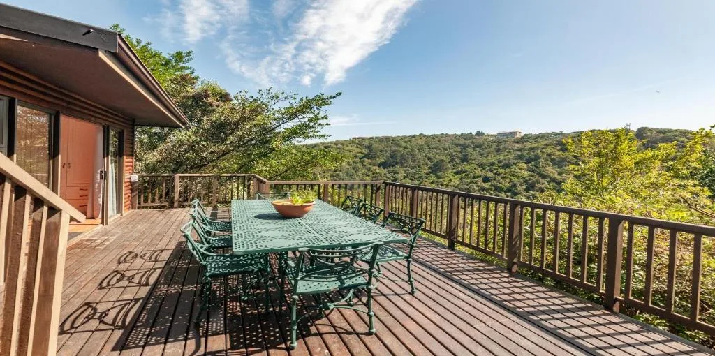Wooden deck with dining table overlooking forested hills and valley