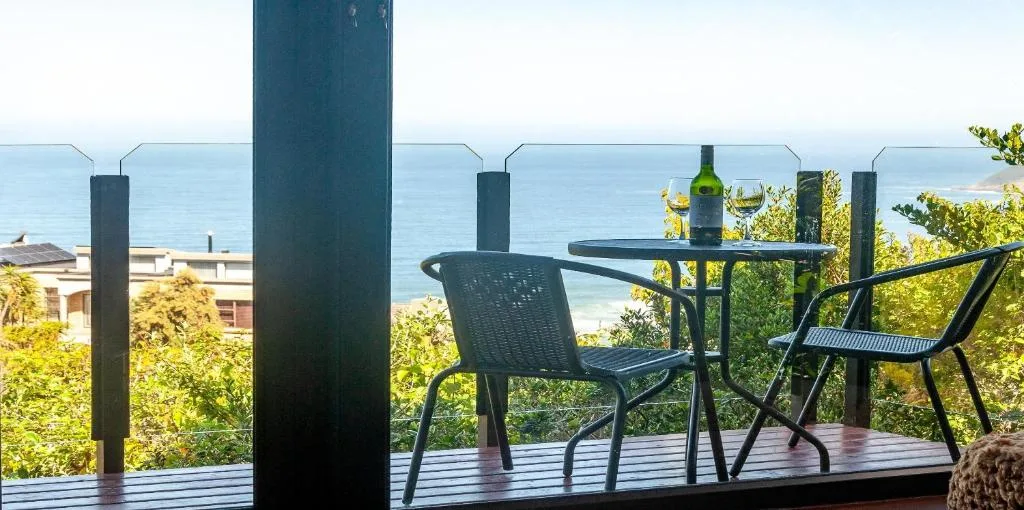Outdoor deck with dining table and chairs overlooking ocean view