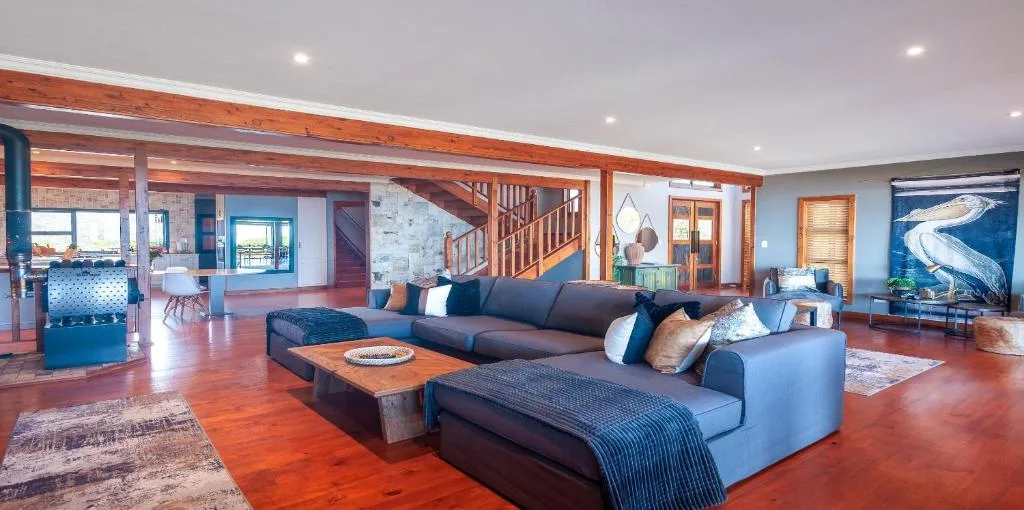 Spacious open-plan lounge with blue sectional sofa and wooden beams