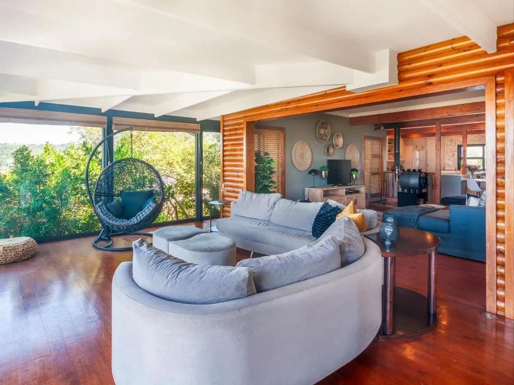 Open-plan lounge with curved grey sectional sofa and hanging chair near large windows