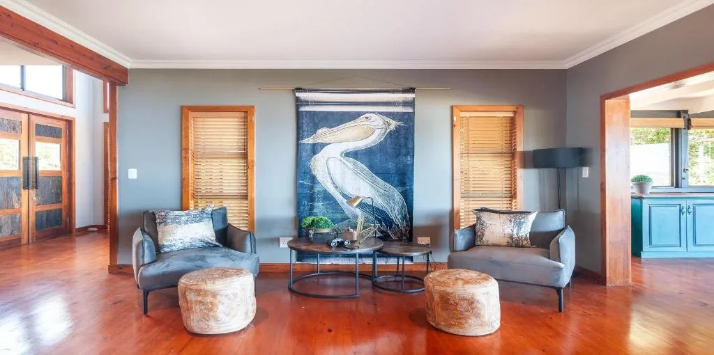 Modern lounge with two grey armchairs, heron artwork, and polished wooden floors