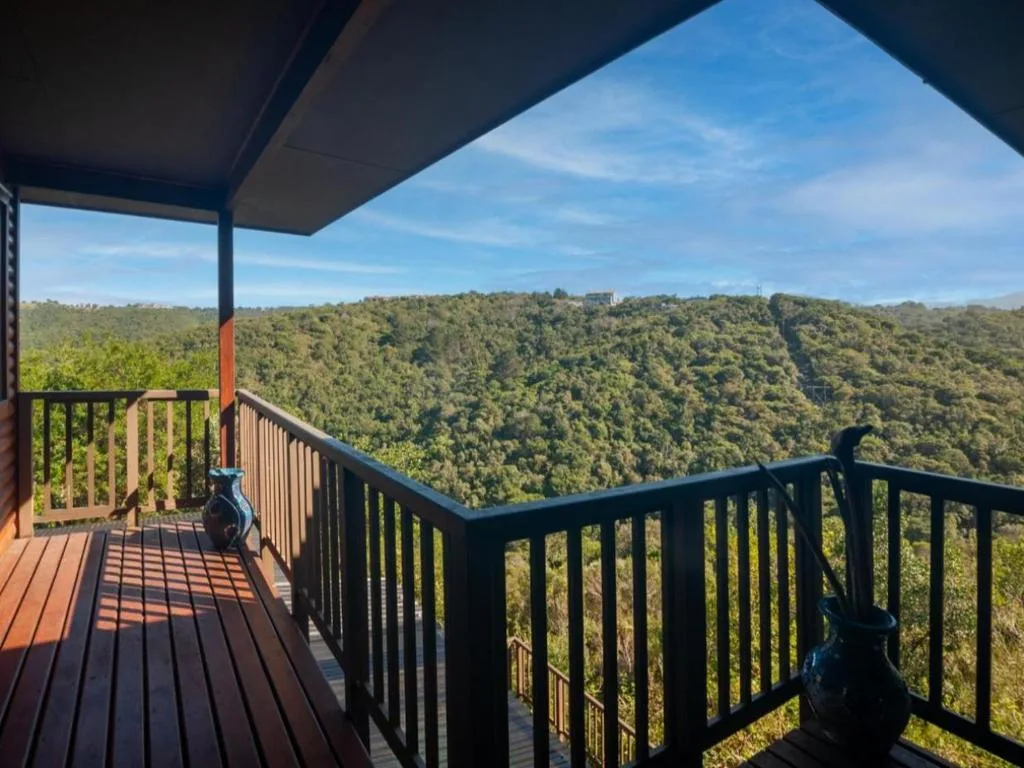 Expansive forested valley landscape visible from covered deck with railing