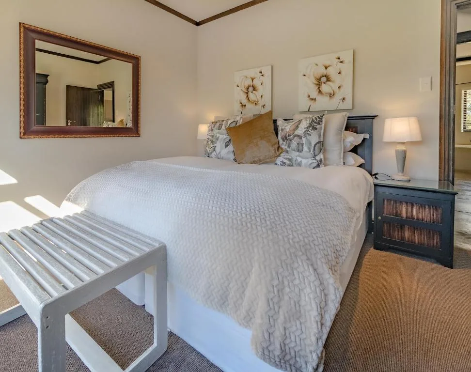 Spacious bedroom with queen bed, floral artwork, and bedside tables