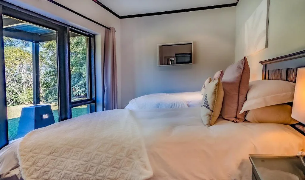 Bright bedroom with two beds, garden views through glass doors
