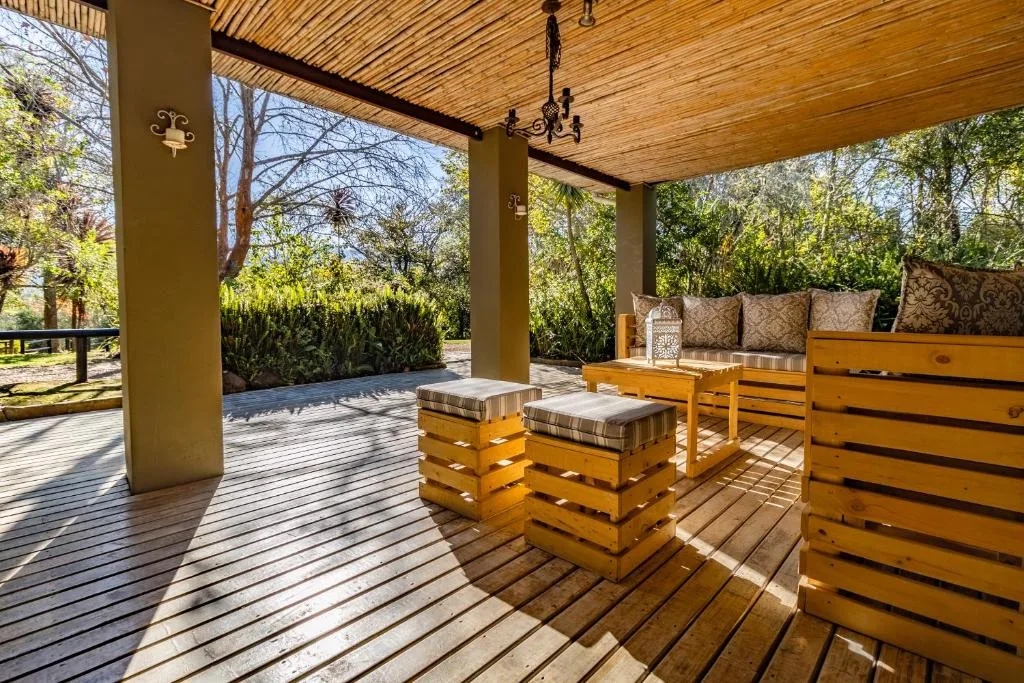 Covered wooden deck with pallet furniture and garden views