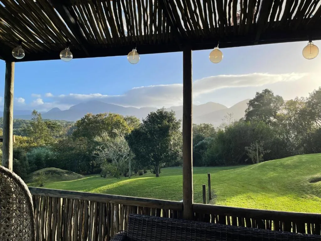 Covered deck with mountain views overlooking lush green gardens and valley landscape