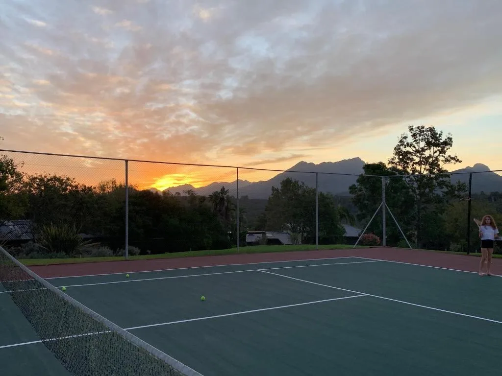 Tennis court at sunset with mountain views and manicured garden surrounds
