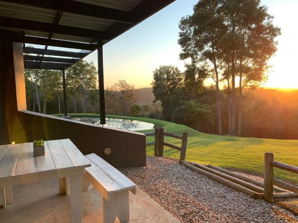 Covered deck with wooden picnic table overlooking sunset and forested valley