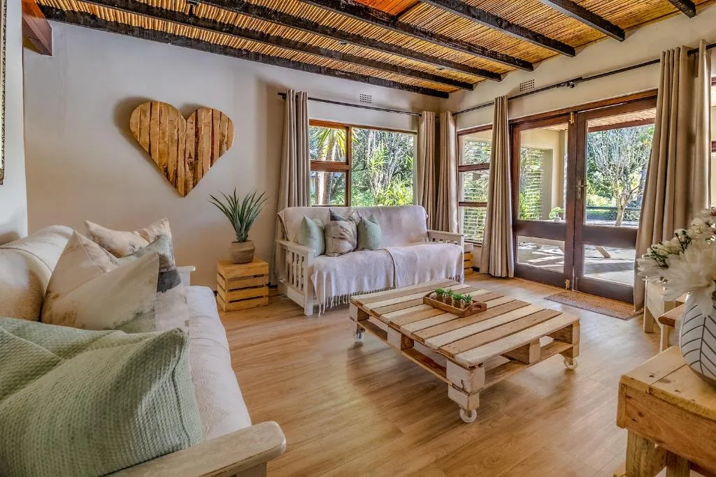 Bright lounge with sofas, wooden beams, and garden views through French doors