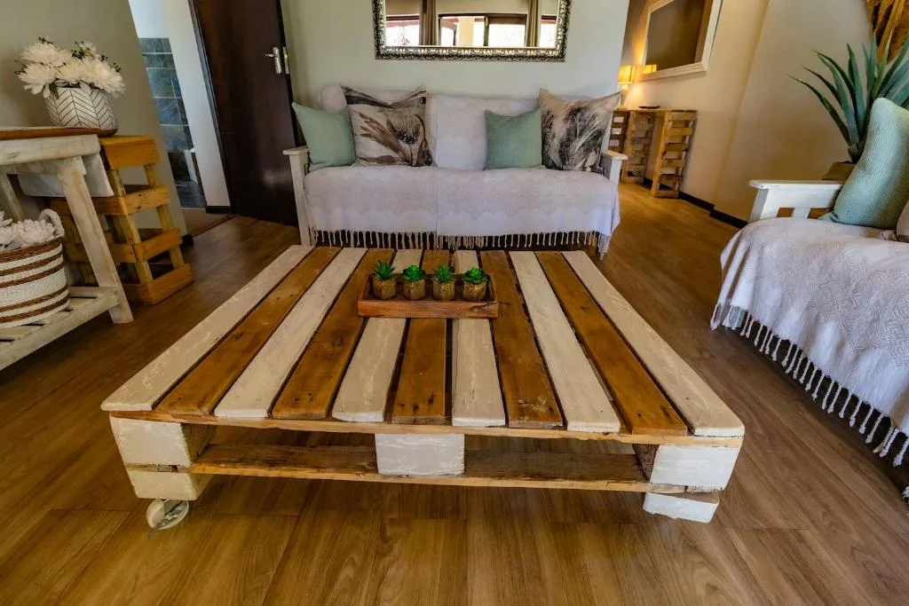 Spacious lounge with sofa, wooden pallet coffee table, potted plants, and wooden flooring
