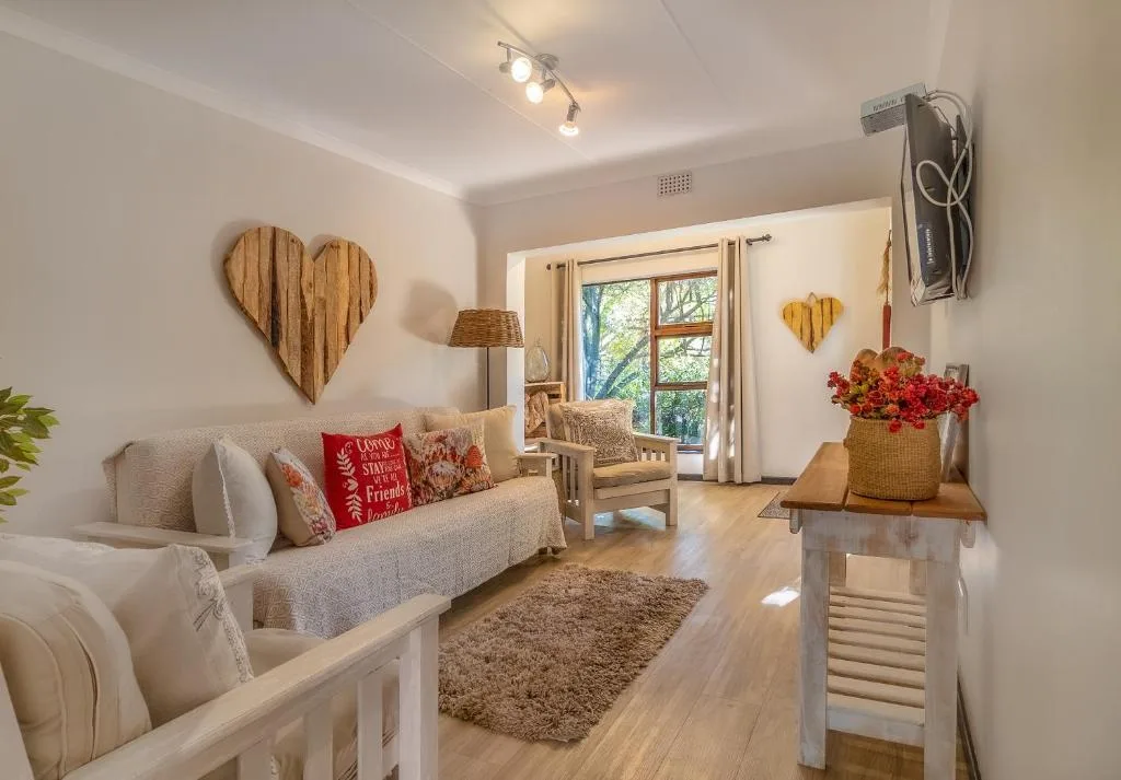 Bright lounge with cream sofa, wooden heart decor, and garden views