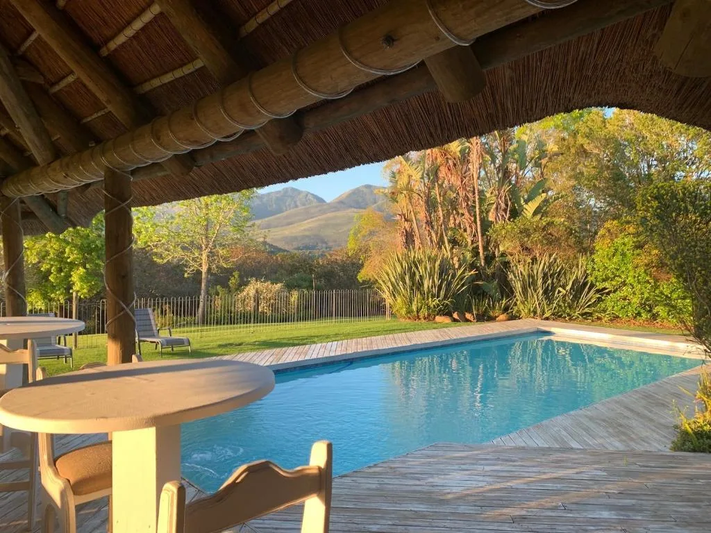 Swimming pool with mountain views, wooden deck, and thatched shelter