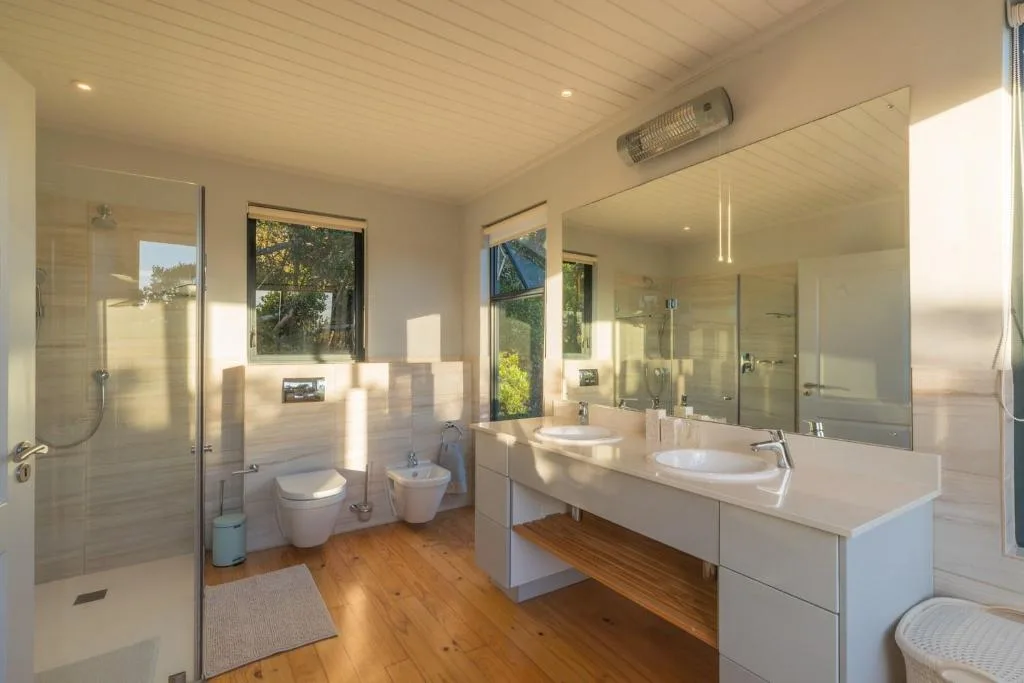 Modern bathroom with dual vanity, shower enclosure, and wooden flooring