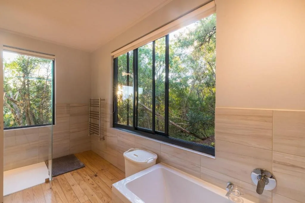 Modern bathroom with soaking tub and forest views through large windows