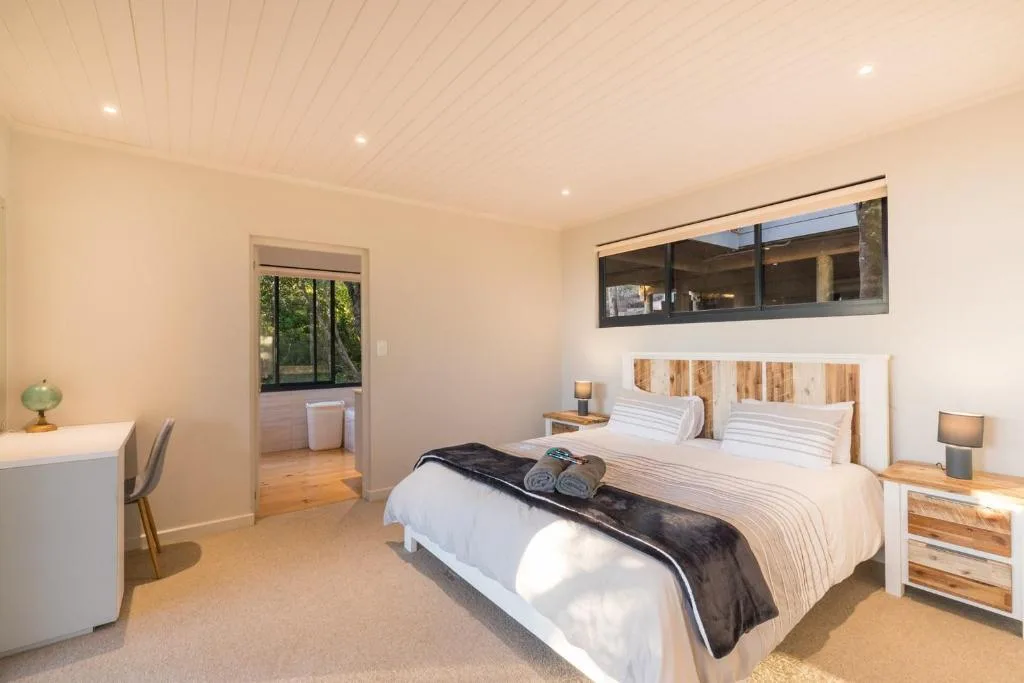 Spacious bedroom with queen bed, wooden headboard, and garden views through sliding doors