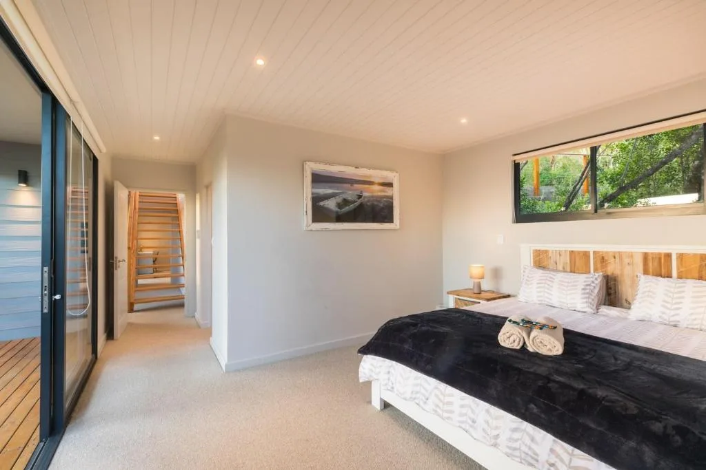 Spacious modern bedroom with wooden headboard and black accent throw