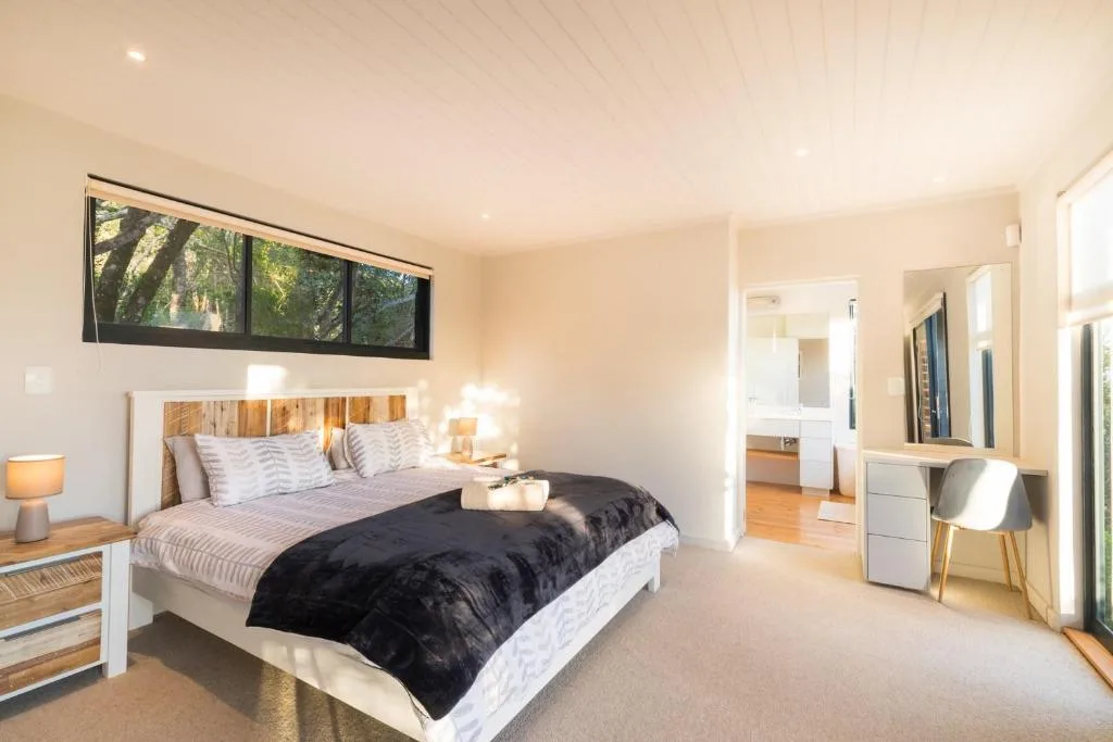 Spacious master bedroom with queen bed, ensuite bathroom visible, garden views