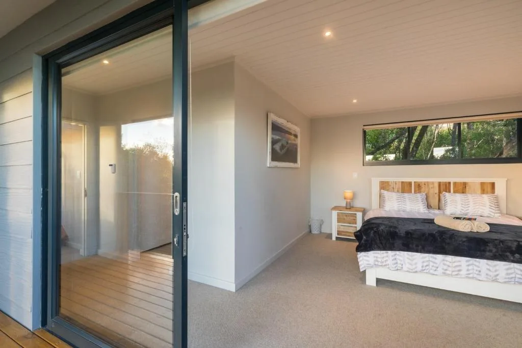 Spacious bedroom with queen bed, wooden headboard, and sliding glass doors opening to deck
