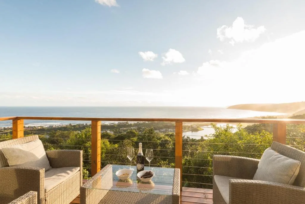 Elevated wooden deck with wicker seating overlooking ocean and lagoon